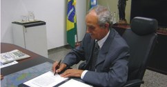 Presidente do TRE, desembargador Josué de Oliveira assinando documento.