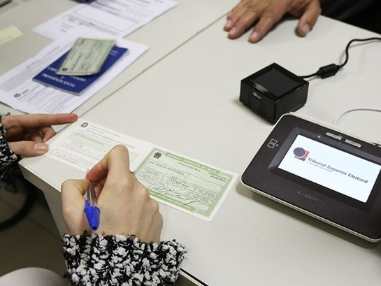 TRE-SC Imprensa Assinatura Cadastramento Biométrico 2019 Eleitora assinando seu título eleitoral.